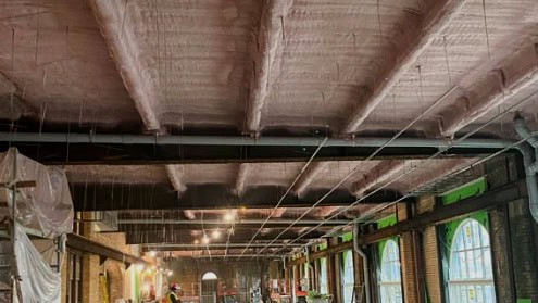 Ceiling with spray foam insulation applied in a large industrial building.