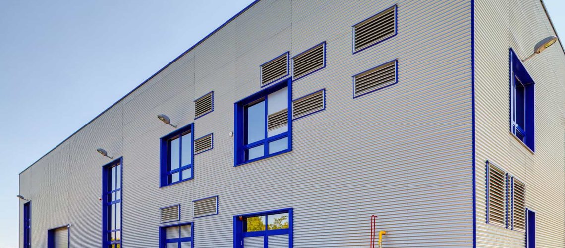 Details of gray facade made of aluminum panels  with doors and windows on industrial building